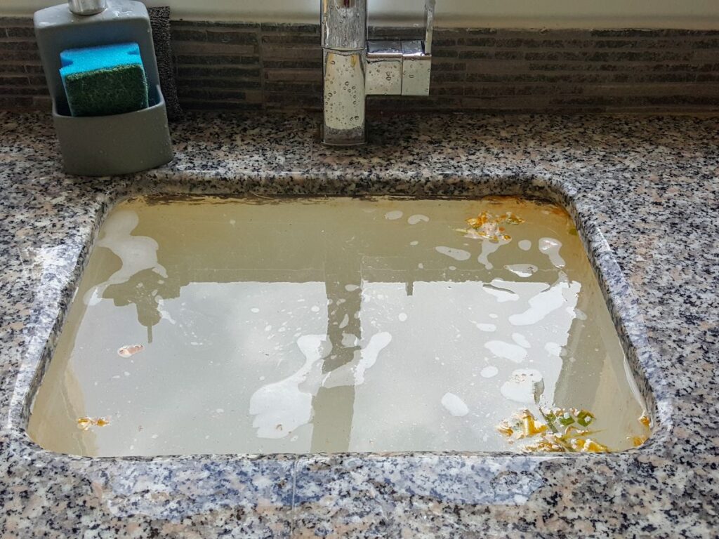 kitchen sink overflowing with murky water