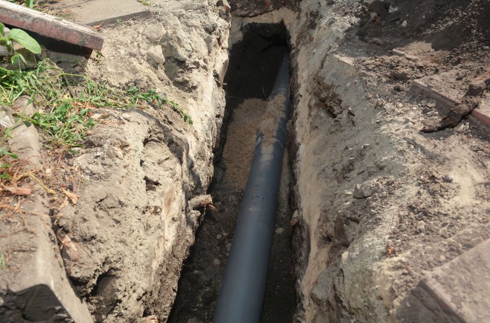 Sewer pipe laid in a narrow trench.